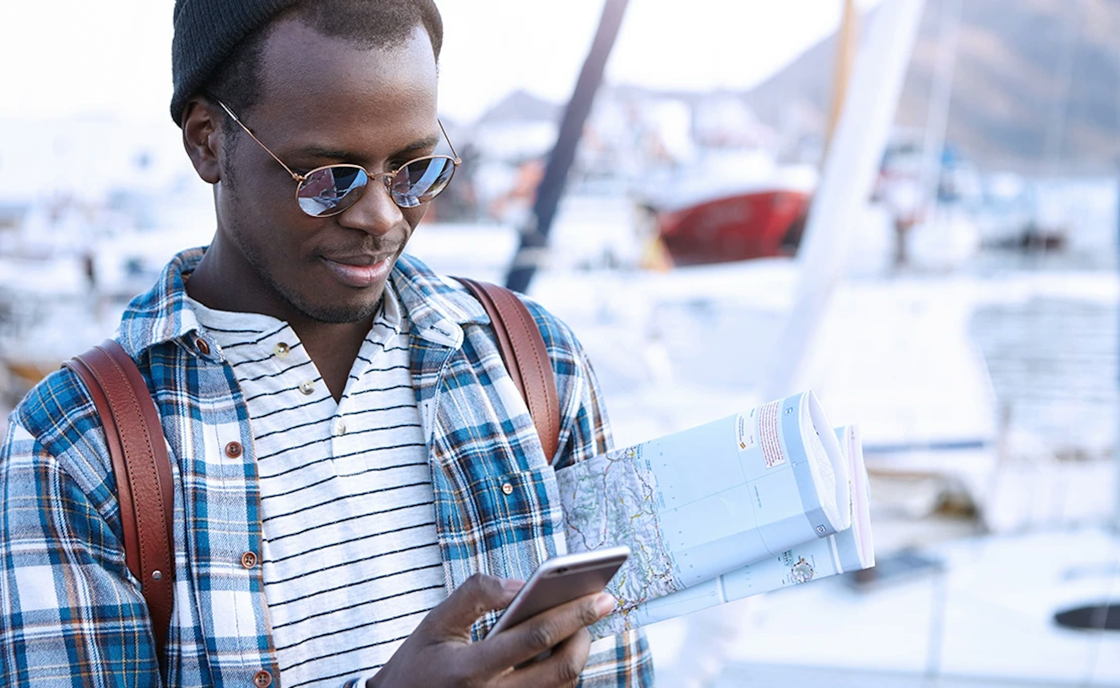 Man looks down at his phone, map under his left armpit.