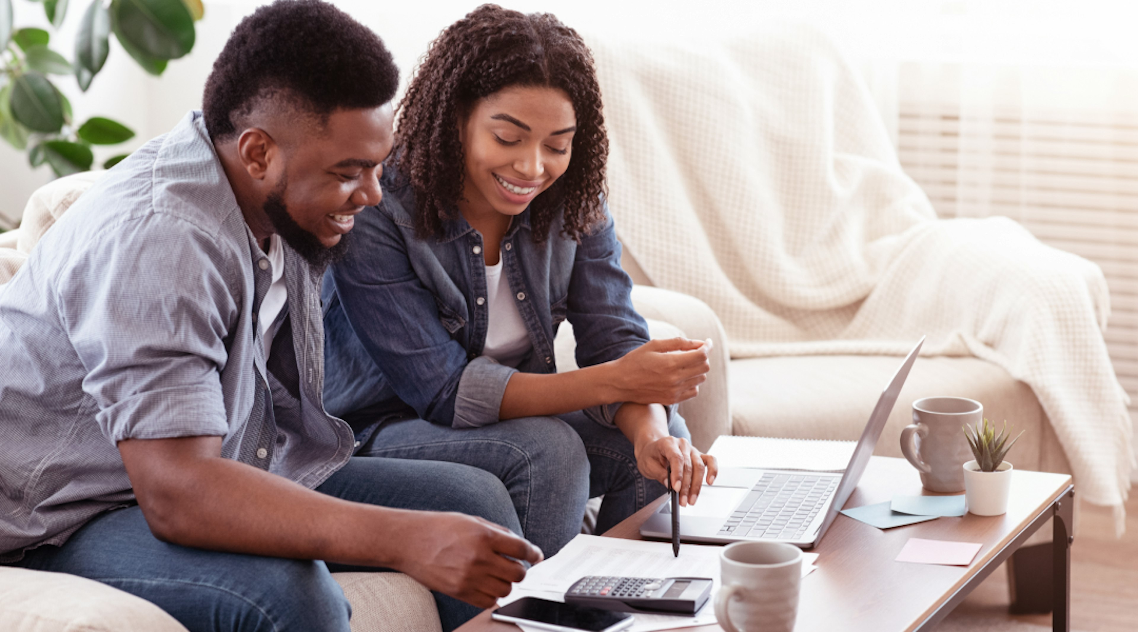 A couple sits on the couch reviewing finance papers