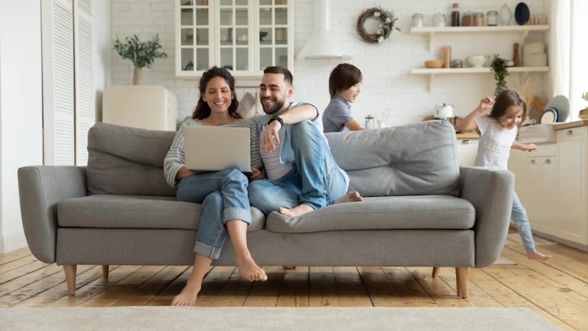 Parents on a laptop using Ibotta to save money on a big purchase sit on a couch together