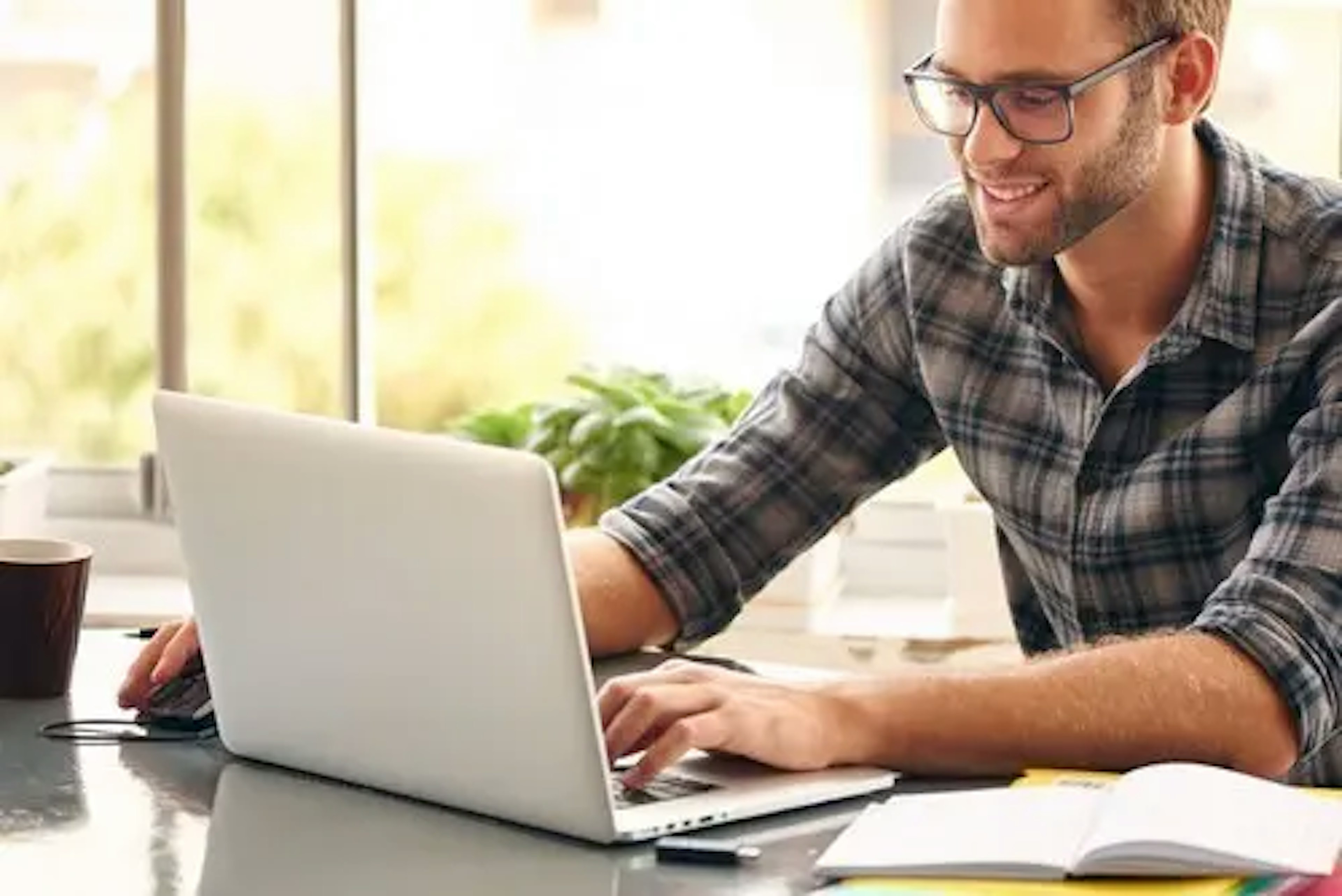 Man sits at desk and smiles at a laptop