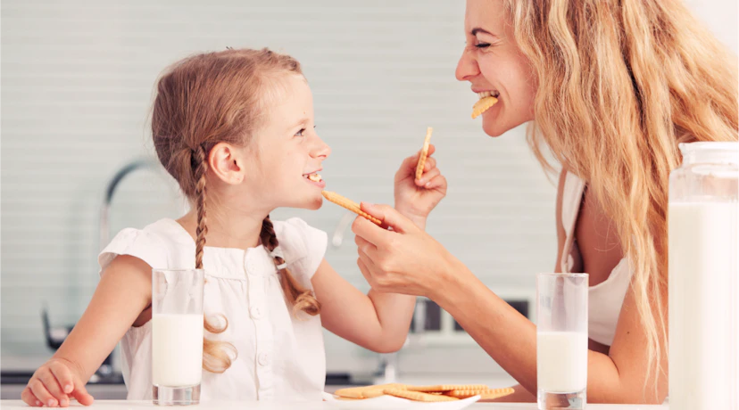 mother and daughter eating cookies and milk