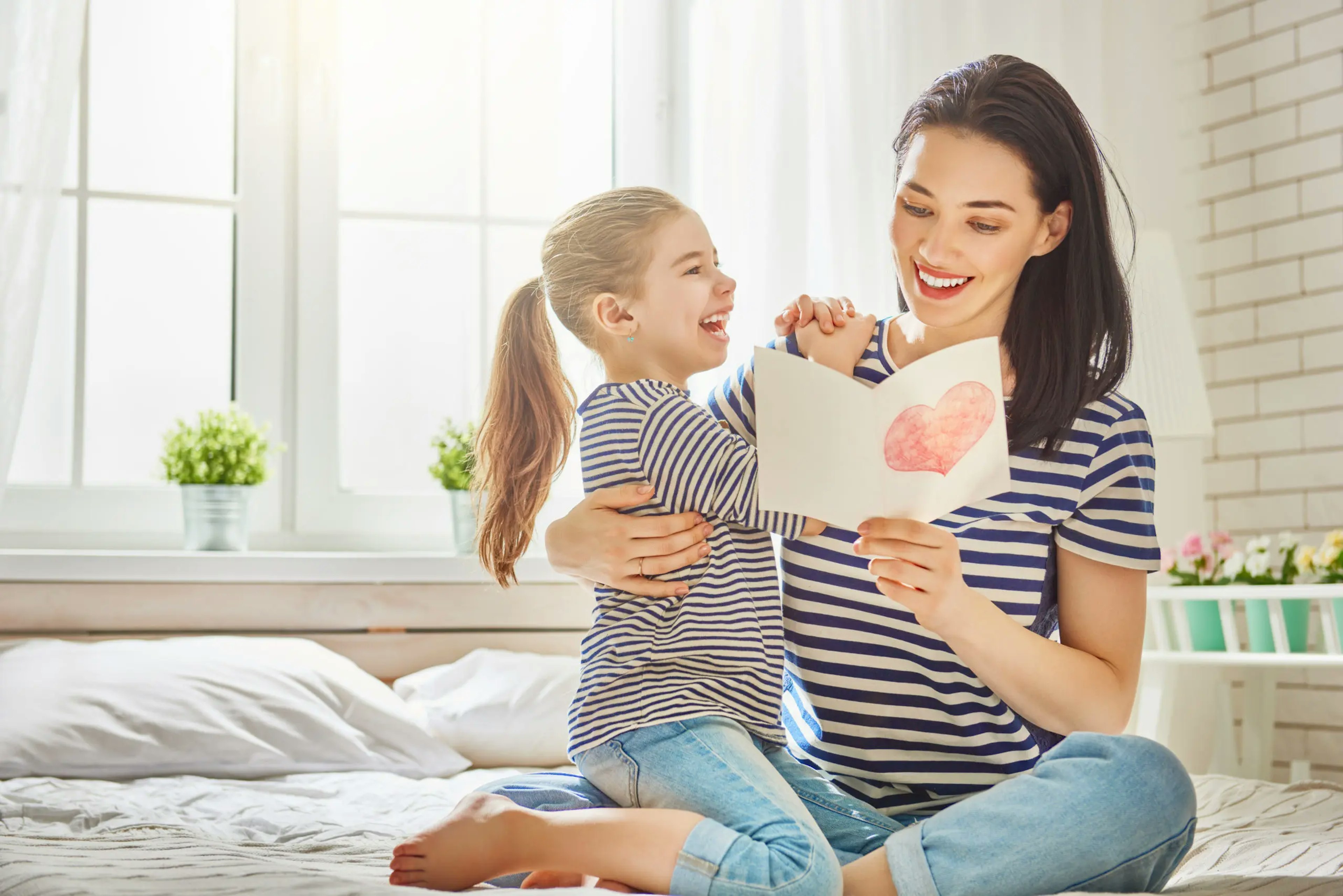 A mother reads a hand written card from her little daughter, smiling