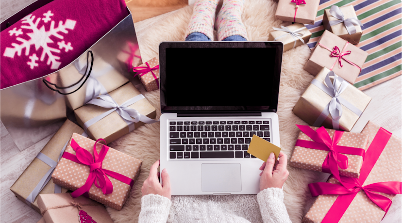 A computer laptop surrounded by wrapped gifts with pink bows